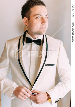 Half-length portrait of the groom buttoning the jacket and looking aside. Half-length portrait of the groom buttoning the jacket and looking aside. 42259455