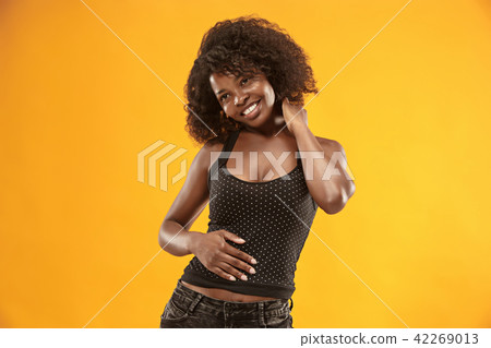 The happy business woman standing and smiling against gold background. 42269013