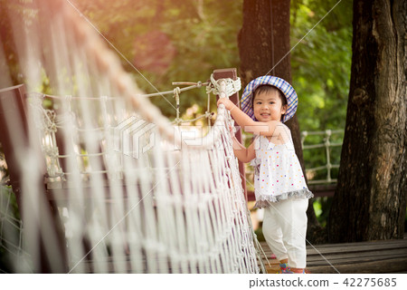 Little girl playing climbing on the rope bridge 42275685