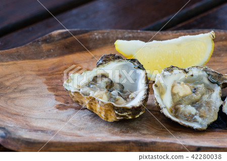 Oysters with lemon on wooden plate. Oysters with lemon on wooden plate. 42280038