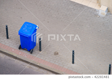 Blue trash can on street pavement Blue trash can on street pavement 42281481