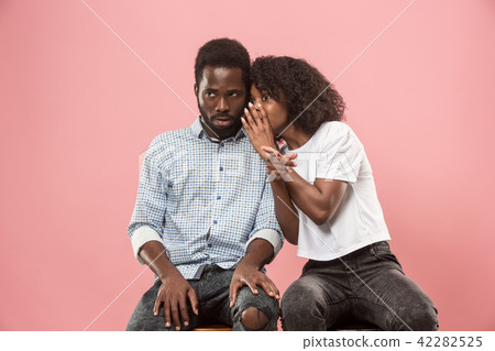 The young woman whispering a secret behind her hand to afro man 42282525