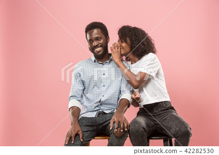 The young woman whispering a secret behind her hand to afro man 42282530