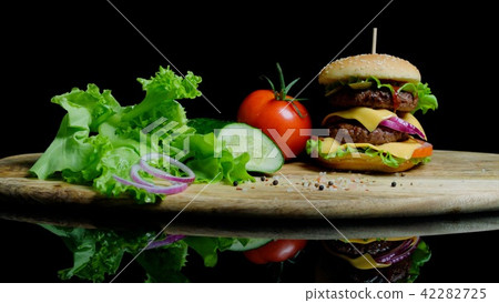 Fresh vegetables and tasty burger with cheese and beef cutlets on the black background Fresh vegetables and tasty burger with cheese and beef cutlets on the black background 42282725