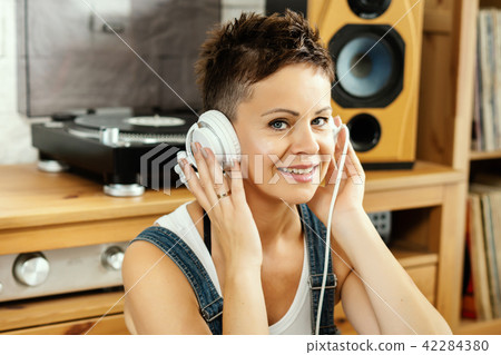 woman with short hair and headphones listens to music woman with short hair and headphones listens to music 42284380