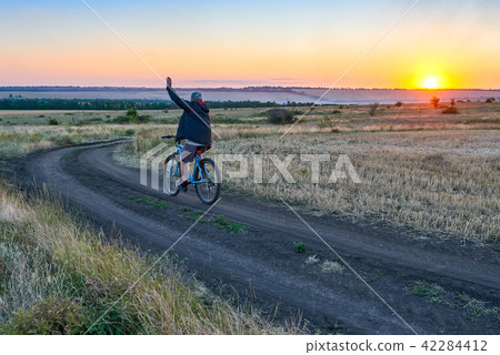 man ride a bike in the country field at sunset 42284412