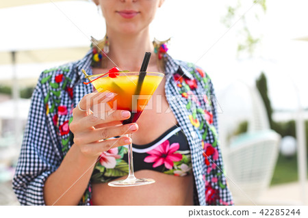 Exotic cocktail glass in womans hand Exotic cocktail glass in womans hand 42285244