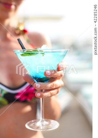 Exotic cocktail glass in womans hand Exotic cocktail glass in womans hand 42285246