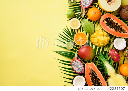 Exotic fruits and tropical palm leaves on pastel 42285307