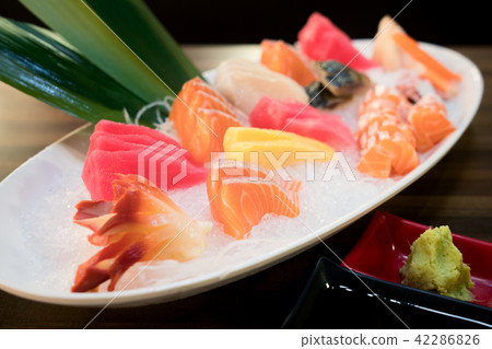 Mixed sliced fish sashimi on ice in white bowl. Mixed sliced fish sashimi on ice in white bowl. 42286826