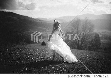 Black and white photograph. Rear view of fragile bride walking on the hill 42287574
