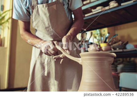 Creating a jar or vase of white clay close-up. Master crock. Man hands making clay jug macro. 42289536