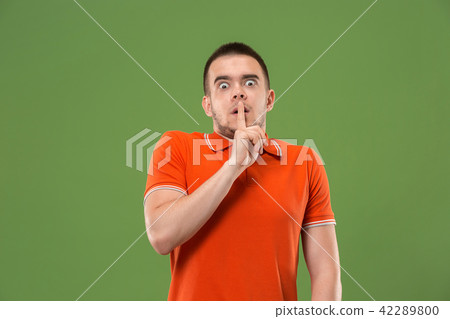 The young man whispering a secret behind her hand over green background The young man whispering a secret behind her hand over green background 42289800