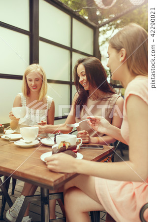 Two girl friends spend time together drinking coffee in the cafe, having breakfast and dessert. Two girl friends spend time together drinking coffee in the cafe, having breakfast and dessert. 42290021