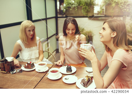 Two girl friends spend time together drinking coffee in the cafe, having breakfast and dessert. Two girl friends spend time together drinking coffee in the cafe, having breakfast and dessert. 42290034
