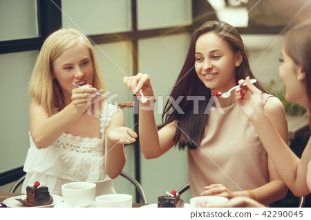 Two girl friends spend time together drinking coffee in the cafe, having breakfast and dessert. Two girl friends spend time together drinking coffee in the cafe, having breakfast and dessert. 42290045