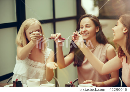 Two girl friends spend time together drinking coffee in the cafe, having breakfast and dessert. Two girl friends spend time together drinking coffee in the cafe, having breakfast and dessert. 42290046