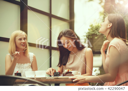 Two girl friends spend time together drinking coffee in the cafe, having breakfast and dessert. Two girl friends spend time together drinking coffee in the cafe, having breakfast and dessert. 42290047
