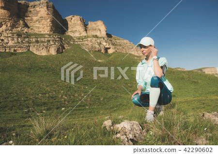 Athlete cute girl in cap with headphones getting ready to run on nature campus. Rest after and 42290602