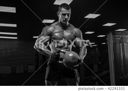 Black and white photo. A handsome man in the gym, with a perfect Black and white photo. A handsome man in the gym, with a perfect 42291331