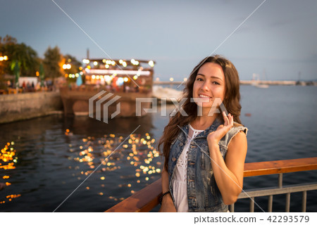 Pretty young woman walking on city promenade near sea in the evening Pretty young woman walking on city promenade near sea in the evening 42293579