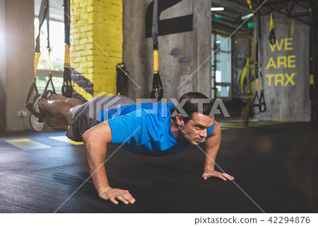 Focused male taking exercise with trx Focused male taking exercise with trx 42294876