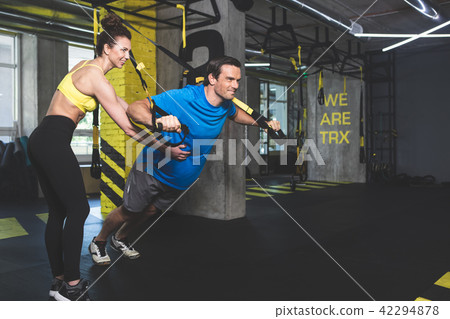 Positive male doing physical exercise with trainer Positive male doing physical exercise with trainer 42294878