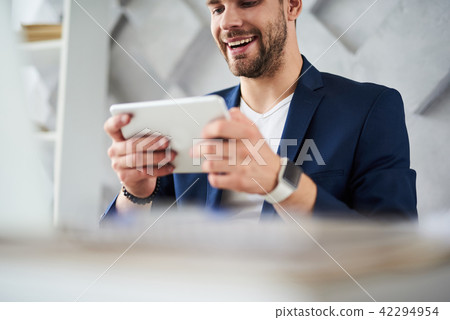 Cheerful man having fun with portative device in office 42294954