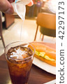 pouring creamer into ice tea during breakfast 42297173
