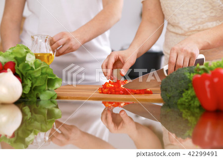 Closeup of human hands cooking in kitchen. Mother and daughter or two female friends cutting 42299491