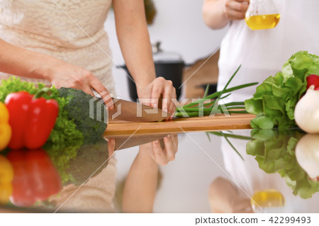 Closeup of human hands cooking in kitchen. Mother and daughter or two female friends cutting 42299493