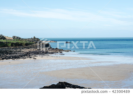 A sandy coast where a shallow tide surrounded by rocky places and hills was drawn at the outskirts of the UK 42300489