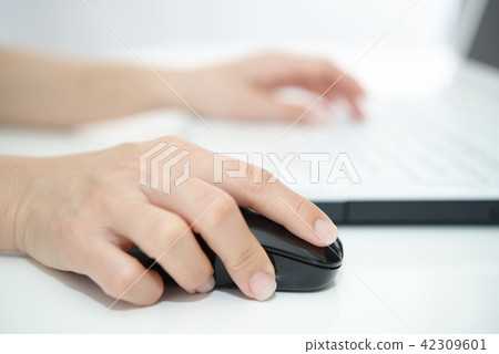 A woman's hand to operate a laptop computer A woman's hand to operate a laptop computer 42309601