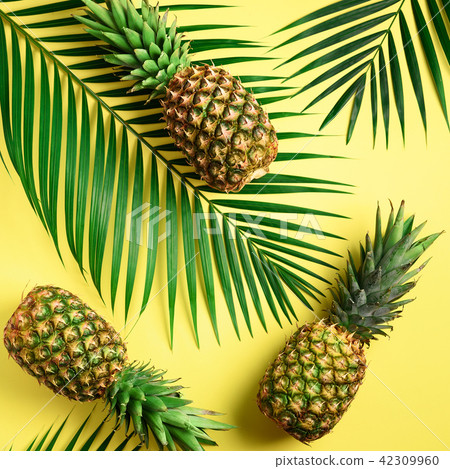Pineapple and tropical palm leaves on yellow 42309960