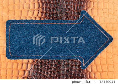 Pointer made of denim is lying on a brown skin 42310034