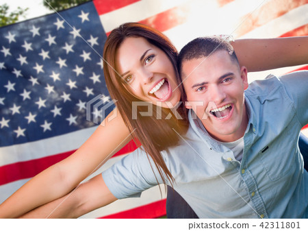 Military Couple Piggy Riding In Front of American Flag 42311801