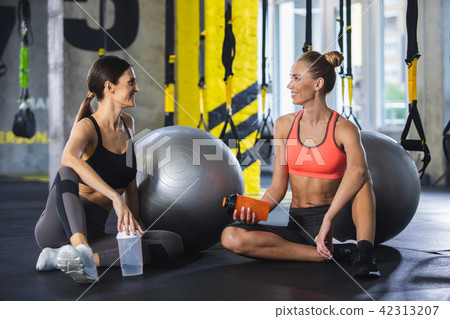 Smiling women are chatting with drink after work out Smiling women are chatting with drink after work out 42313207