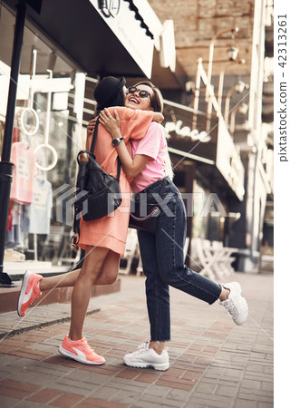 Happy girls hugging at street Happy girls hugging at street 42313261