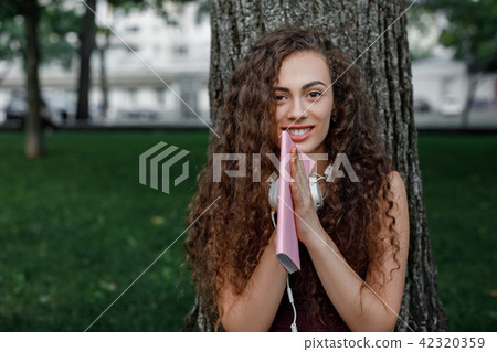 girl student holding book and sitting under tree girl student holding book and sitting under tree 42320359