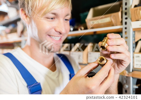 Close-up of the hands of a worker holding two pipe fitting accessories Close-up of the hands of a worker holding two pipe fitting accessories 42324101