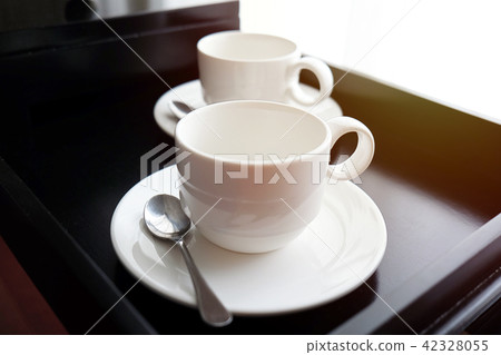 White coffee mug with spoon on black tray 42328055