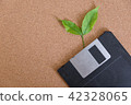 A diskette grows out of a sheet on a wooden floor. 42328065