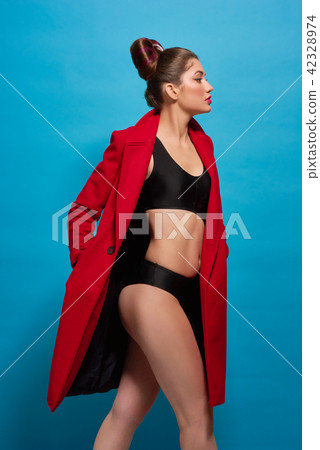 Sideview of moving model with slim figure wearing red coat, black lingerie. Sideview of moving model with slim figure wearing red coat, black lingerie. 42328974