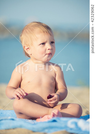 Cute baby playing with toys on sandy beach near the sea. 42329062