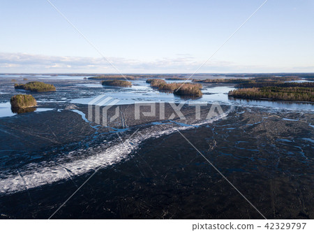 Melting ice cover cracking at lake in spring 42329797