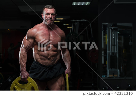 Strong mature man with relief body posing in gym Strong mature man with relief body posing in gym 42331310