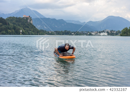young man exercising on paddle board at the lake young man exercising on paddle board at the lake 42332287