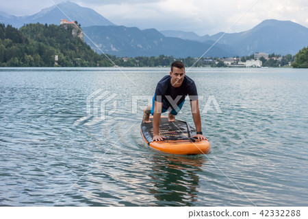 young man exercising on paddle board at the lake 42332288