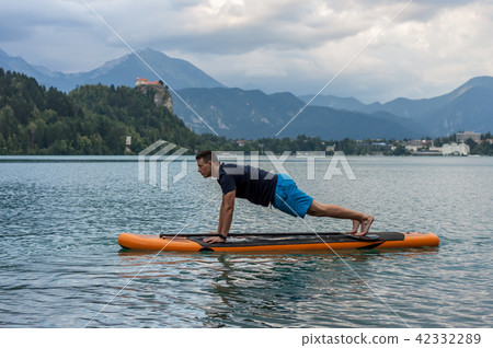 young man exercising on paddle board at the lake young man exercising on paddle board at the lake 42332289