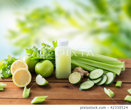close up of bottle with green juice and vegetables close up of bottle with green juice and vegetables 42338524